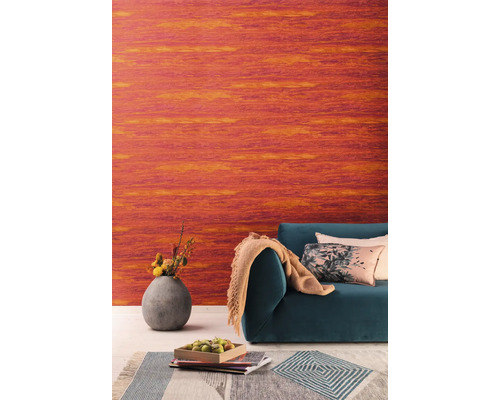 Salon avec papier peint vinyle orange, canapé, coussins et vase de fleurs