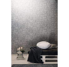 Pièce à vivre avec papier peint structuré gris, coussins et plaid sur une palette