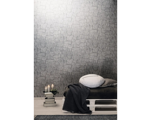 Pièce à vivre avec papier peint structuré gris, coussins et plaid sur une palette