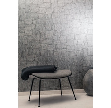 Mur avec papier peint à motif de briques grises, tabouret et jeté de lit