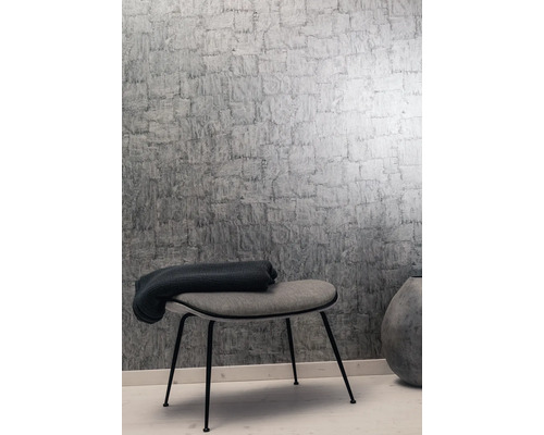 Mur avec papier peint à motif de briques grises, tabouret et jeté de lit