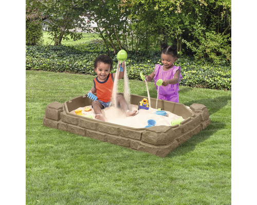 Bac à sable en plastique avec des enfants qui jouent dans le jardin.