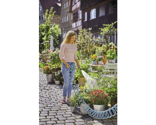 Une femme arrose des fleurs avec un tuyau d''arrosage dans le jardin.
