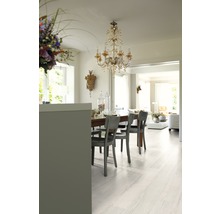 Salle à manger avec table, chaises et plancher en bois clair.