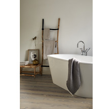 Badezimmer mit freistehender Badewanne, Handtuchleiter und Holzbank