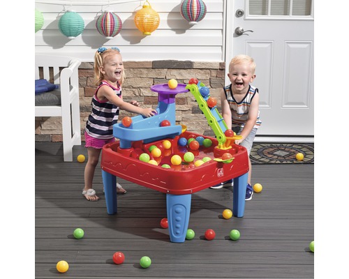 Deux enfants jouent avec une table de jeu Step2 avec des balles colorées à l''extérieur.