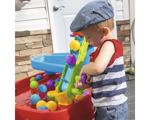 Enfant jouant avec une table d''eau et de balles à l''extérieur