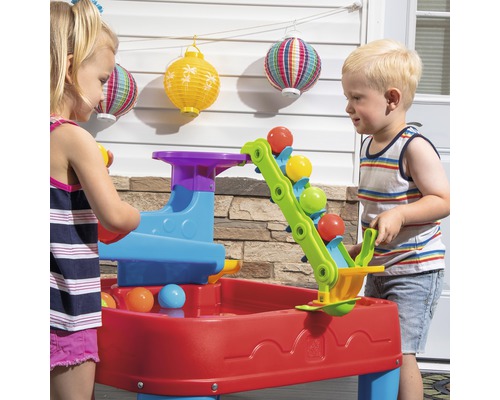 Deux enfants jouent avec une table d''eau à billes Step2 colorée à l''extérieur.