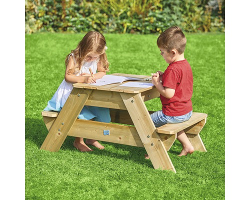 Deux enfants sont assis à une table de pique-nique en bois dans le jardin et dessinent.