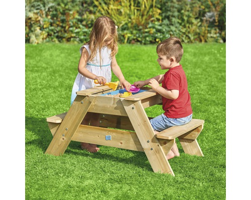 Deux enfants jouent sur une table de pique-nique en bois avec fonction de bac à sable dans le jardin.