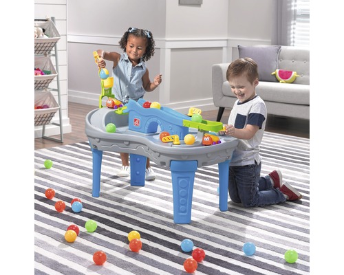 Deux enfants jouent avec une table de jeu Step2 avec des rampes et des balles