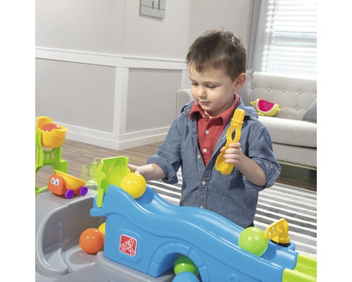 Un enfant joue avec un circuit de balles Step2 avec des balles et une pelle.