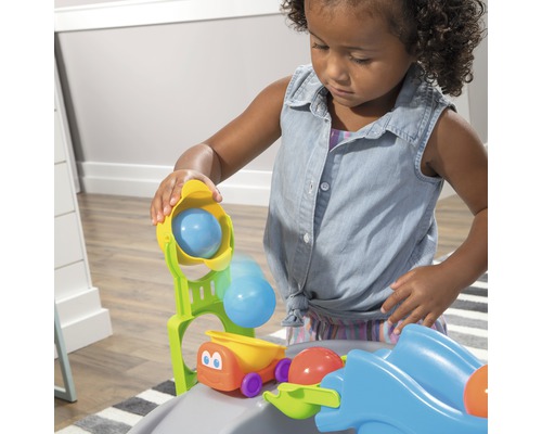 Un enfant joue avec un circuit de billes avec des véhicules.