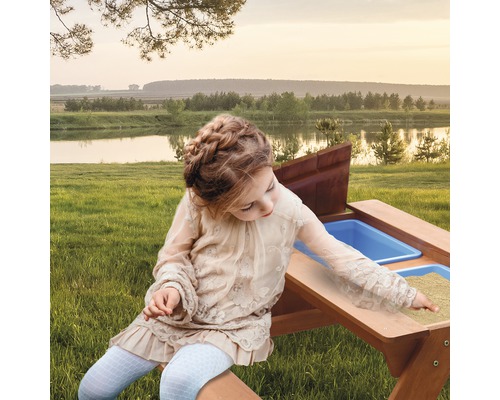 Fille jouant à une table de sable et d''eau dans le jardin.