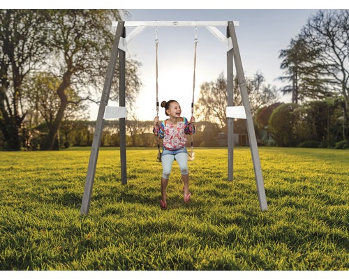 Fille se balançant sur une balançoire en bois dans le jardin