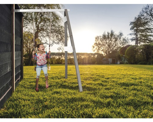 Fille se balançant sur une balançoire en bois dans le jardin