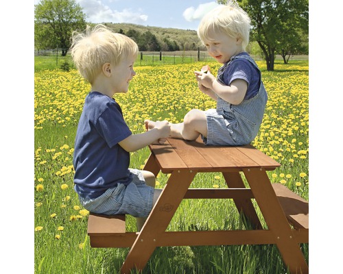 Deux enfants sont assis à une table de pique-nique en bois à l''extérieur.