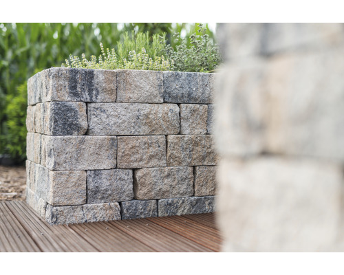 Jardinière surélevée en blocs de pierre sur une terrasse en bois avec des plantes