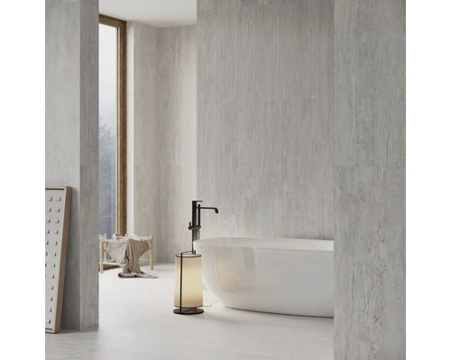 Salle de bains lumineuse avec carrelage, baignoire et lampadaire