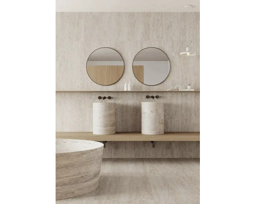 Salle de bain lumineuse avec double vasque en pierre naturelle, miroirs ronds et baignoire assortie.