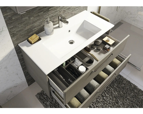 Salle de bain avec meuble sous-lavabo, lavabo, robinetterie et tiroirs ouverts avec accessoires de bain et serviettes