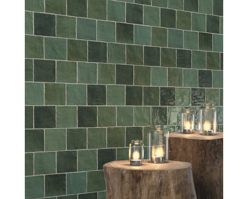 Mur carrelé avec de petits carreaux carrés et décoration avec des photophores sur des souches d''arbres