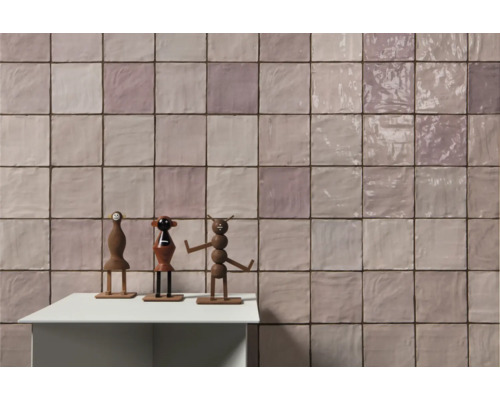 Wandfliesen in quadratischer Anordnung mit drei Holzfiguren auf einem Tisch