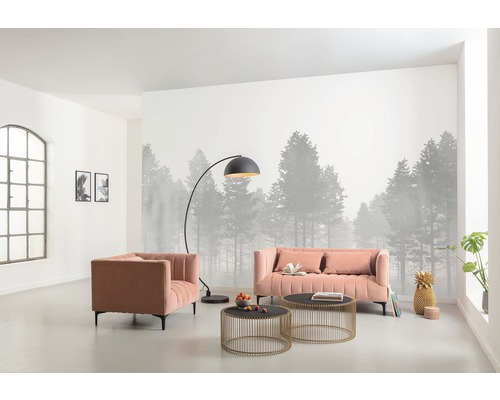 Salon avec canapé, fauteuil, lampadaire et tables basses devant un papier peint photo avec motif de forêt.