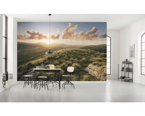 Pièce lumineuse avec papier peint photo d''un paysage de collines au lever du soleil et un groupe de tables à manger