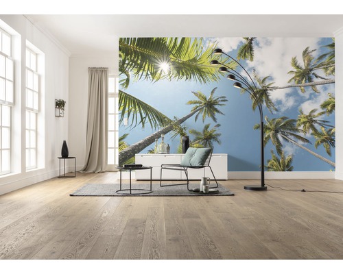 Salon avec papier peint photo avec motif de palmier, lampadaire, fauteuil et table