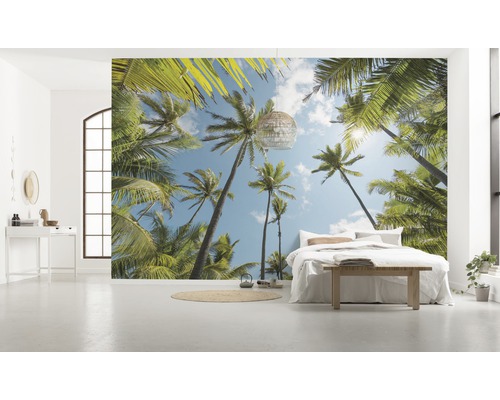 Chambre lumineuse avec papier peint photo à motif de palmiers, lit et décoration