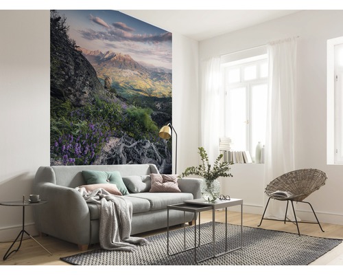 Salon lumineux avec canapé, tapis et papier peint photo avec un motif de montagne