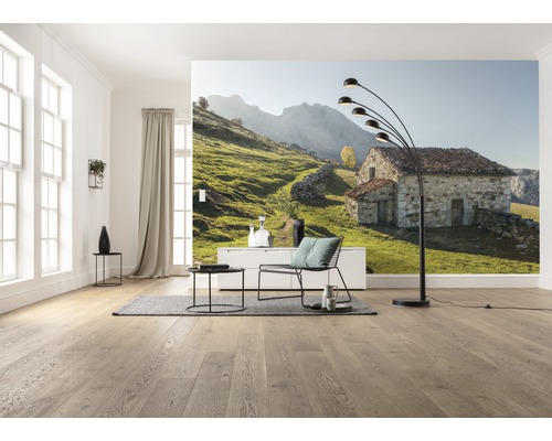 Salon avec papier peint photo d''une maison en pierre dans un paysage de collines verdoyantes