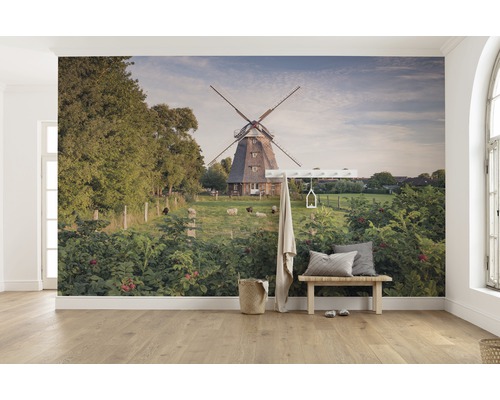 Papier peint représentant un moulin à vent, des moutons et une végétation luxuriante dans une pièce lumineuse.