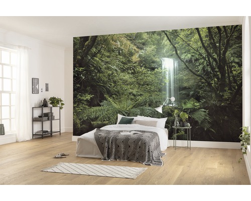 Chambre lumineuse avec papier peint photo d''une forêt avec cascade, lit avec couverture et table de chevet
