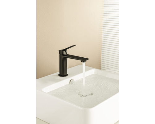 Robinet noir sur un lavabo blanc avec de l''eau qui coule.