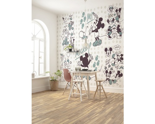Une salle à manger avec une table à manger, des chaises et un mur avec des motifs Mickey Mouse.