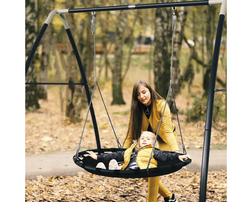 Mère et enfant sur une balançoire ronde dans le jardin