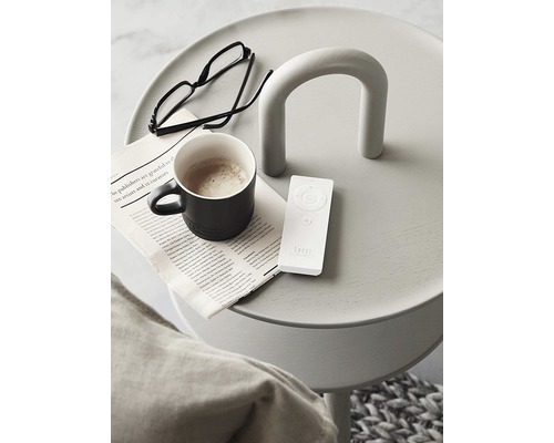 Dekorativer Beistelltisch mit Zeitung, Brille, Kaffeetasse und Fernbedienung