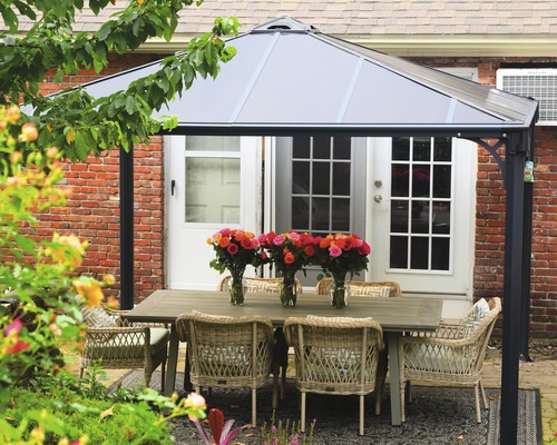 Scène de jardin avec pavillon, table à manger et chaises à l''extérieur.