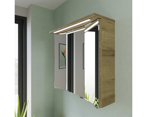 Spiegelschrank aus Holz mit Beleuchtung und drei Spiegeltüren an einer grünen Wand