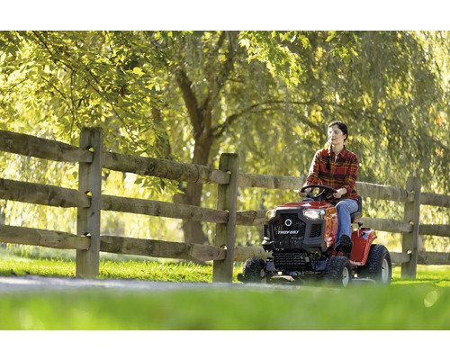Une femme conduit un tracteur de jardin sur une pelouse