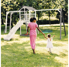 Aire de jeux avec tour, toboggan et balançoire pour enfants dans le jardin.