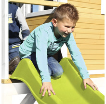 Garçon glissant sur un toboggan vert d''une cabane de jeu