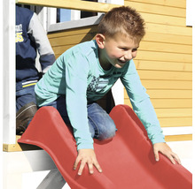 Kind rutscht auf einer roten Rutsche an einem Spielhaus