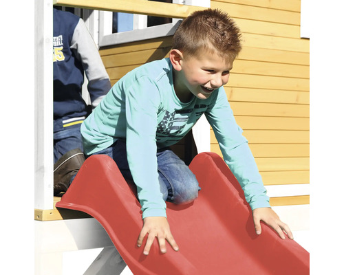 Enfant glissant sur un toboggan rouge sur une cabane de jeu