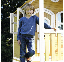 Garçon debout devant une cabane en bois avec une fenêtre ouverte