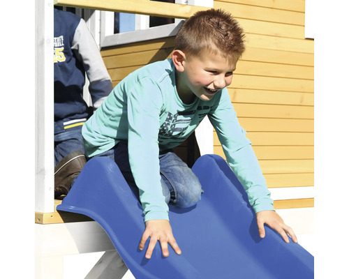 Enfant glissant sur un toboggan bleu d''une cabane de jeu.