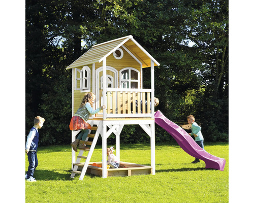 Maisonnette avec toboggan et bac à sable dans le jardin avec des enfants qui jouent.