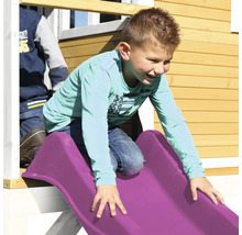 Un garçon glisse sur un toboggan en plastique d''une aire de jeux.